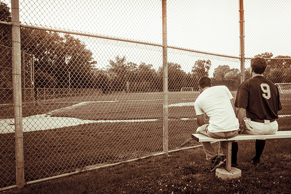 two boys sitting on baseball field bench
