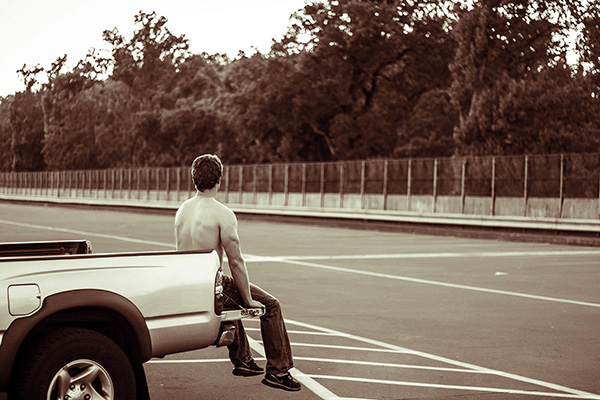 boy sitting on back of truck